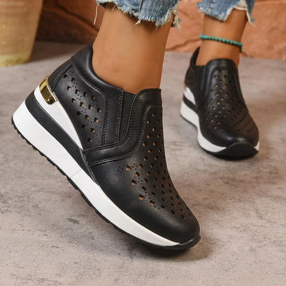 Black perforated Quorin women's wedge sneakers with a subtle heart pattern and gold heel accent, shown on a model's feet.