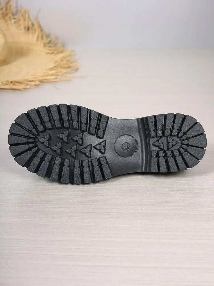Close-up view of the chunky black rubber lug sole of a platform loafer, showcasing its deep tread pattern and durable construction.