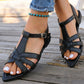 Woman's feet wearing elegant black pointed-toe flat sandals with interwoven straps and a slingback closure, styled with distressed jeans on a wooden deck.