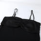 Close-up view of a black camisole top featuring a lustrous satin-like ruched bust and thin adjustable spaghetti straps against a white background.