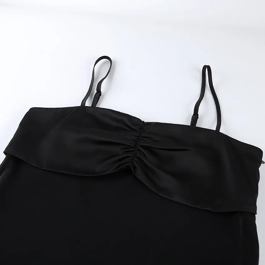 Close-up view of a black camisole top featuring a lustrous satin-like ruched bust and thin adjustable spaghetti straps against a white background.