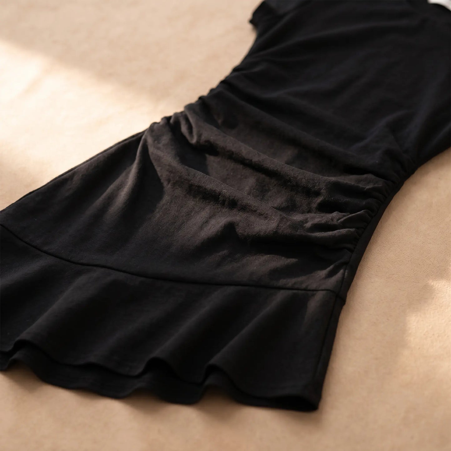 Close-up of the Jaryth premium cotton ruched asymmetrical dress, highlighting the distinctive side waist ruching and elegant fluted hem detail in black.