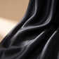 Detailed view of the black satin midi skirt fabric, highlighting its luxurious luminous sheen and fluid, elegant drapes. Smooth premium texture visible.