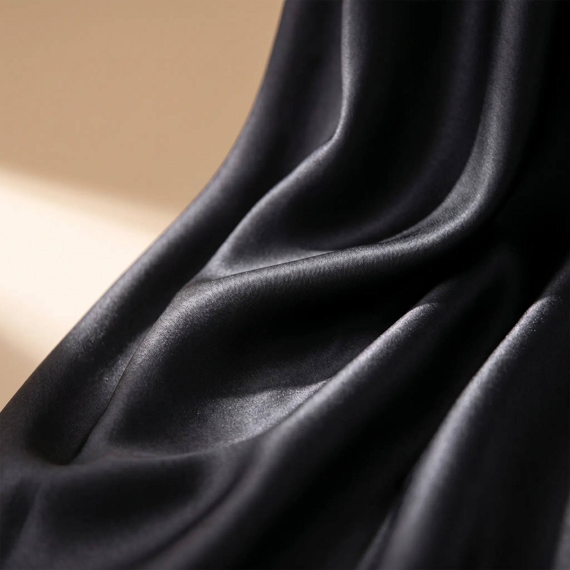 Detailed view of the black satin midi skirt fabric, highlighting its luxurious luminous sheen and fluid, elegant drapes. Smooth premium texture visible.