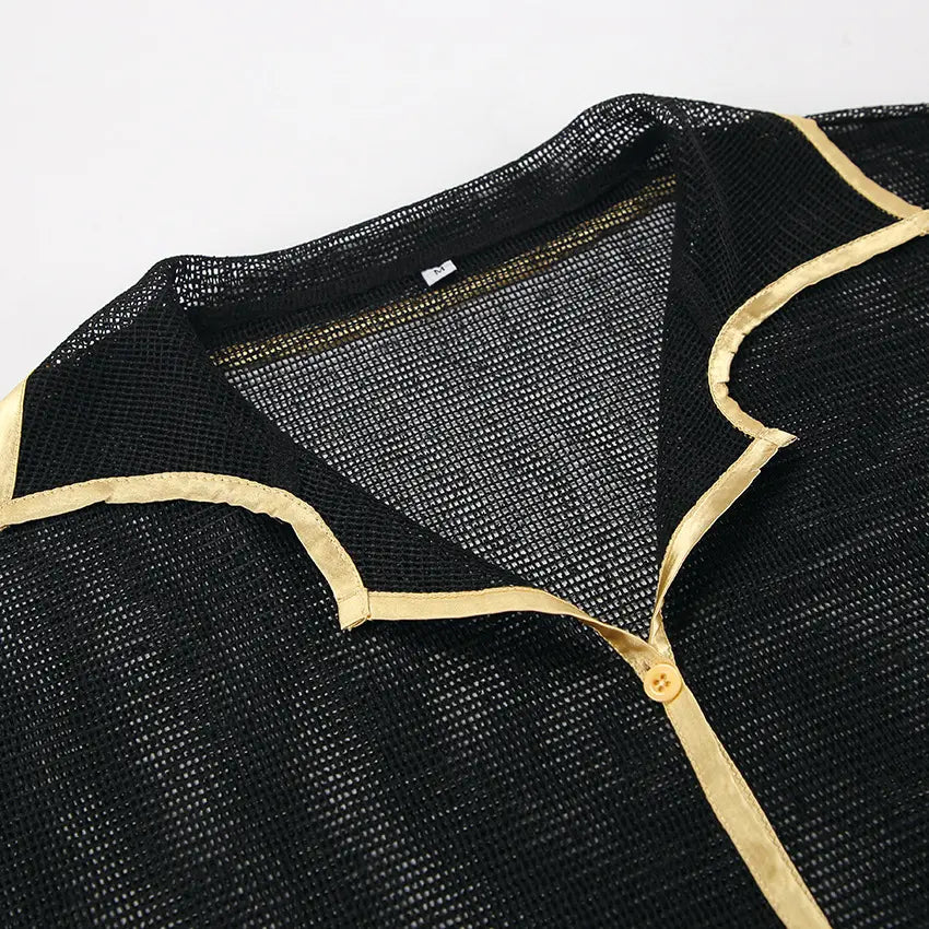 Close-up view of black sheer mesh fabric with contrasting gold piping trim on a lounge set collar, featuring a tonal button detail.