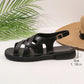Side view of elegant black synthetic leather strappy flat sandals with an adjustable gold-toned buckle and a 3cm rubber sole.