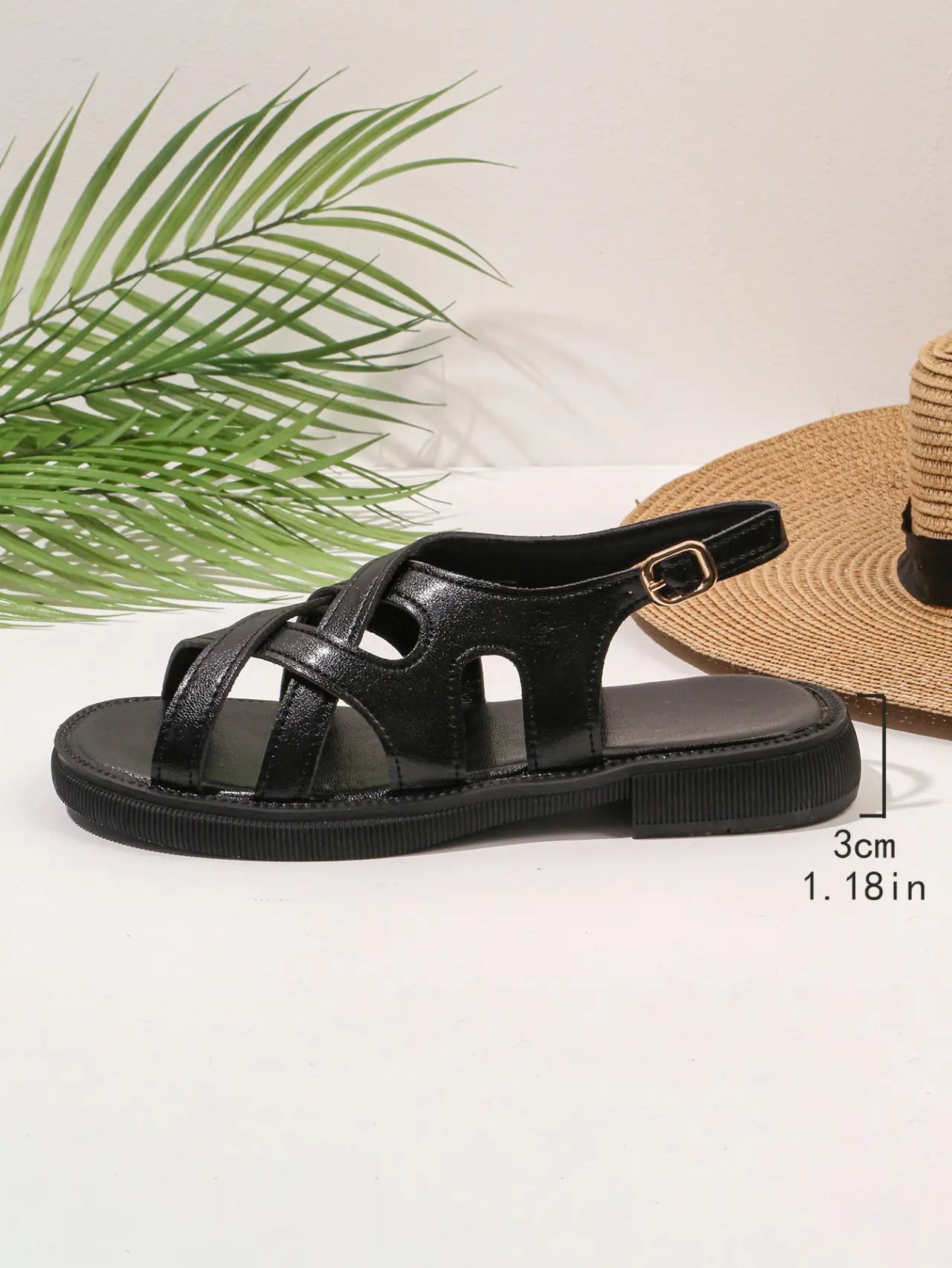 Side view of elegant black synthetic leather strappy flat sandals with an adjustable gold-toned buckle and a 3cm rubber sole.