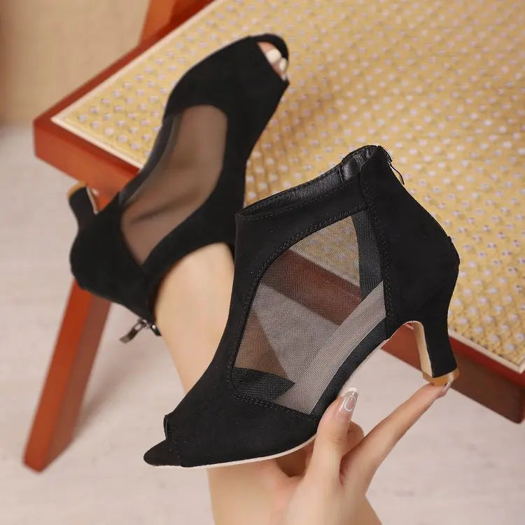 Elegant black suede-like peep-toe ankle boots featuring sheer mesh side panels and a slim stiletto heel, displayed from a three-quarter angle.