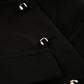 Close-up view of a black tailored sleeveless vest showcasing polished gold-tone square button detailing and textured woven fabric. This detail shot highlights the garment's refined craftsmanship and luxurious hardware.