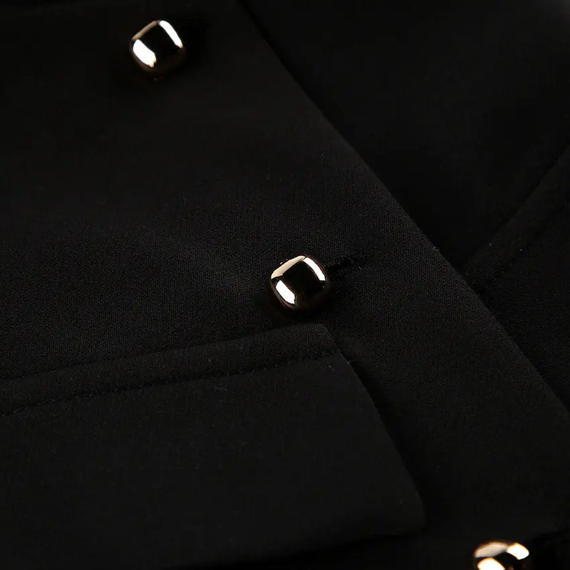 Close-up view of a black tailored sleeveless vest showcasing polished gold-tone square button detailing and textured woven fabric. This detail shot highlights the garment's refined craftsmanship and luxurious hardware.