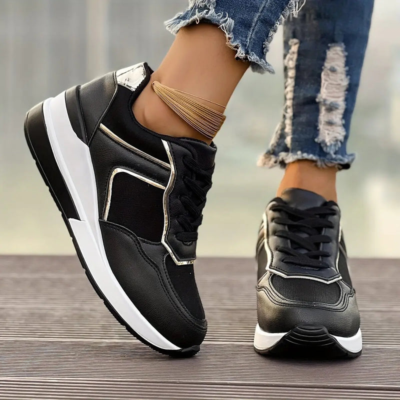 Women's black wedge sneakers with rose gold accents and a layered white and grey sole, worn with distressed denim.