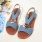 Light blue textured fabric Roman flat sandals with a polished silver-tone metal ring embellishment and elasticated criss-cross slingback straps. The sandals feature a fish mouth peep-toe design and a flat brown footbed with a black rubber sole.