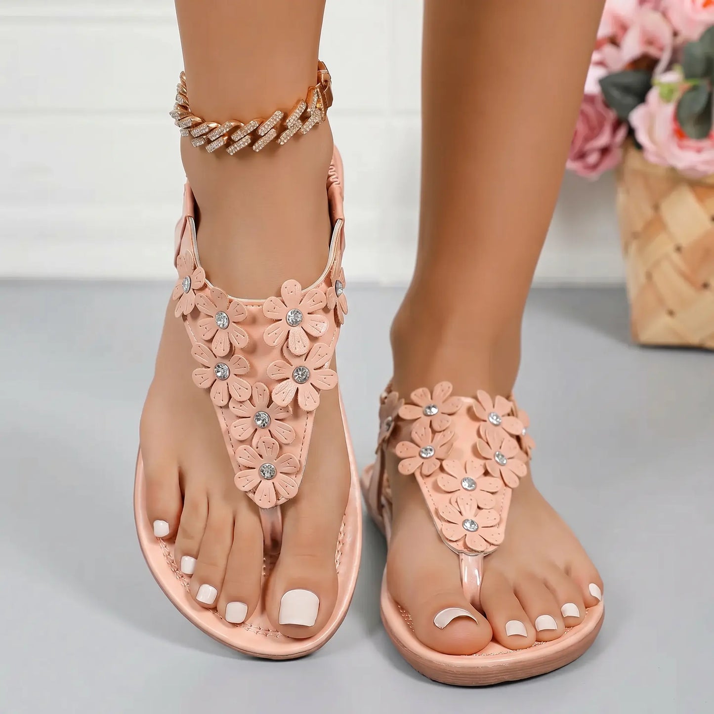 Blush apricot bohemian flat t-strap sandals adorned with 3D floral appliques and crystal accents, shown on feet with an elasticated slingback strap.