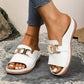 Woman wearing white Brevix chic platform slide sandals with a prominent gold interlocking buckle accent, open-toe design, and comfortable contoured footbed, showcased in a lifestyle setting.