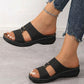 Briska black laser-cut slip-on sandals with a low wedge heel and metallic stud details, styled with ripped jeans.