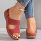 Red Briska laser-cut wedge slip-on sandals with intricate geometric detailing, worn by a model with blue jeans and a beaded anklet.