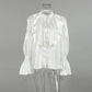 White satin blouse featuring a high stand collar, cascading front ruffles, pearl button placket, and dramatic trumpet sleeves with smocked cuffs.