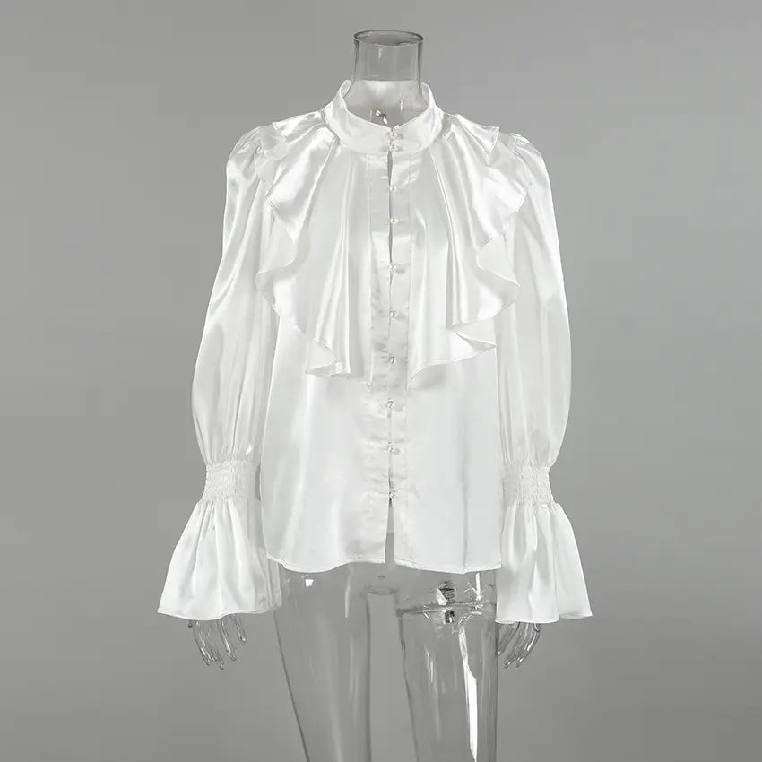 White satin blouse featuring a high stand collar, cascading front ruffles, pearl button placket, and dramatic trumpet sleeves with smocked cuffs.