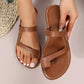 Brown faux leather asymmetrical slide sandals for women, featuring an open-toe design and white contrast stitching on a flat sole.