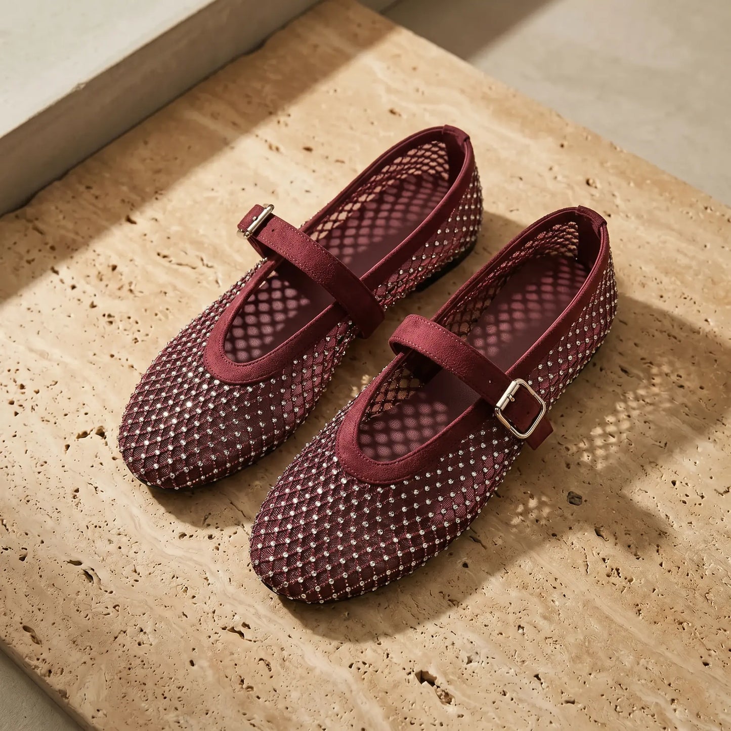 Galdyr Burgundy Wine rhinestone mesh Mary Jane flats with crystal-studded diamond netting and a suede-finish buckle strap, shown from a three-quarter angle on a textured beige surface.
