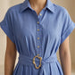 Close-up of the Zivro chambray blue linen-blend midi dress, highlighting the structured point collar, delicate pearlescent buttons on the placket, cuffed short sleeves, and the distinctive gold organic-shaped buckle on the wide fabric belt.