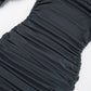 Close-up of a charcoal grey evening dress fabric showcasing intricate all-over asymmetrical ruching and draped texture.