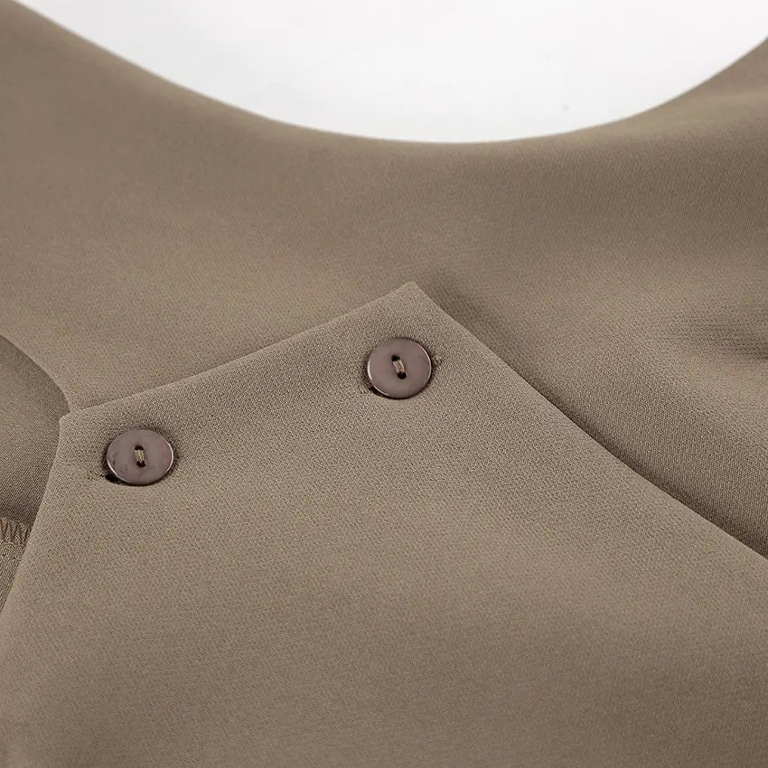 Close-up of a chic beige vest featuring an asymmetrical crossover detail with two small matte buttons at the shoulder area, showcasing fabric texture.