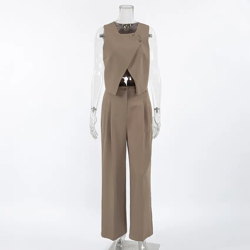 Chic beige women's vest and wide-leg trouser set, featuring an asymmetrical crossover vest with shoulder buttons and high-waisted pleated trousers, shown from the front.