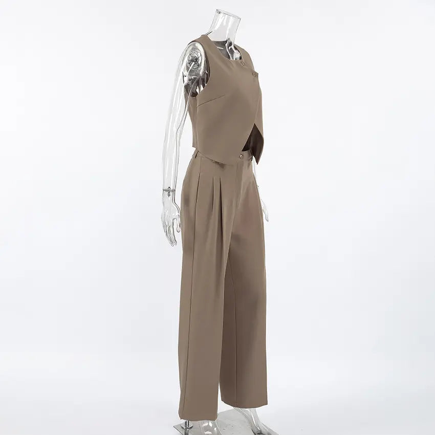 Women's chic beige vest and wide-leg trouser set viewed from the side, featuring an asymmetrical crossover vest and high-waisted pleated trousers. Elegant two-piece co-ord set.
