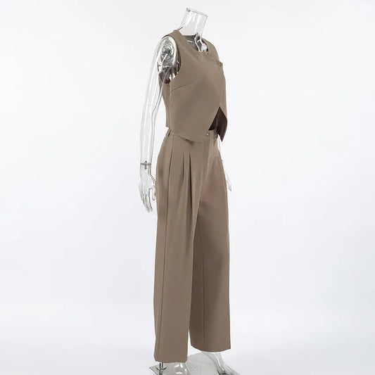 Women's chic beige vest and wide-leg trouser set viewed from the side, featuring an asymmetrical crossover vest and high-waisted pleated trousers. Elegant two-piece co-ord set.