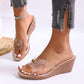 Women's elegant clear strap wedge sandals with a gold pearl accent, shown on a model's foot with white pedicure and distressed jeans.