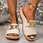 Chic cream platform slide sandals for women, featuring a wide strap with a prominent gold-tone interlocking buckle and a contoured footbed, worn on feet with a sparkling sequined background.