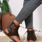 Dark brown faux leather gladiator flat sandals for women, featuring intricate lace-up detailing extending up the ankle and a thong toe post, worn with denim jeans.