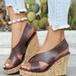 Model's feet wearing dark brown faux leather criss-cross wedge sandals with vibrant multi-color speckles on the cork wedge, styled with light wash jeans.