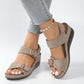 Desert Khaki faux suede wedge sandals with gold buckles and contrast white stitching, shown on a model's feet with casual jeans and an anklet.