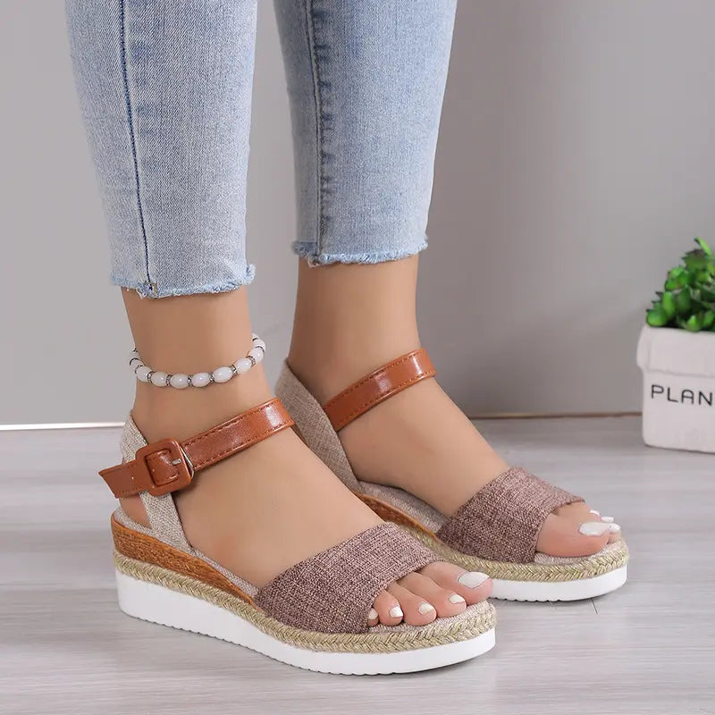 Elarae women's espadrille wedge sandals in a warm beige linen with a tan faux leather ankle strap, worn with blue jeans and a beaded anklet, showcasing the peep-toe and white platform sole.