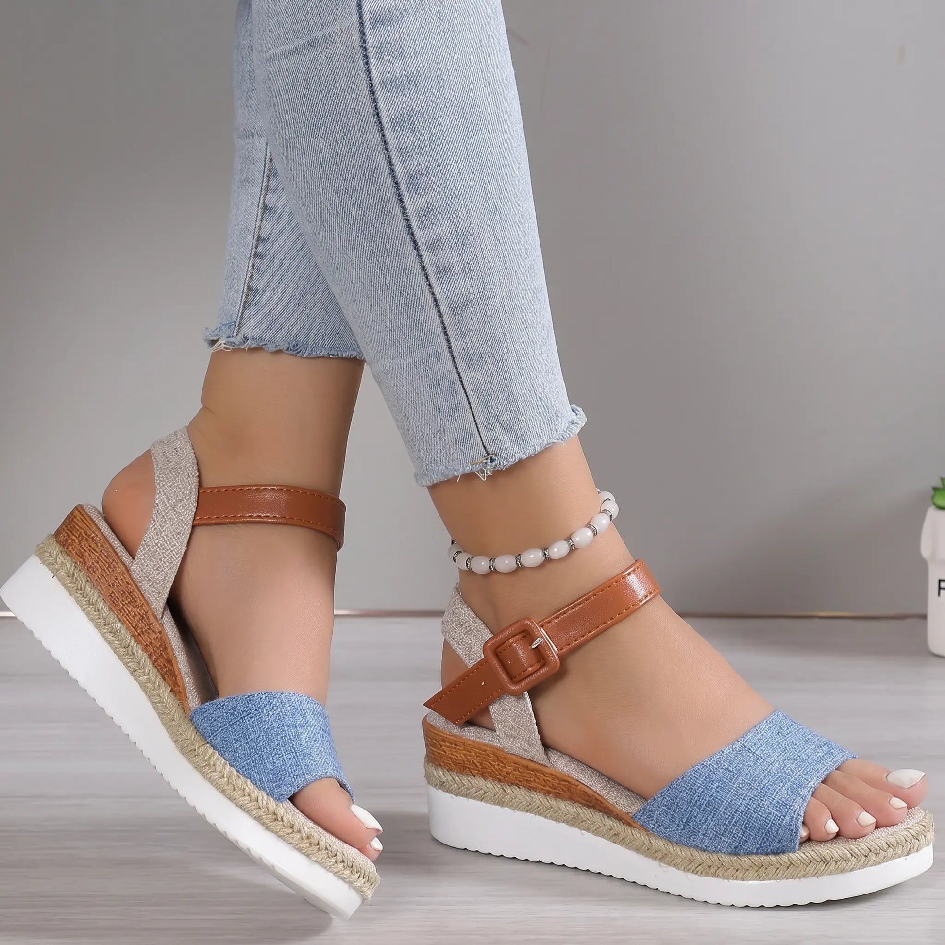 Elarae women's espadrille wedge sandals in denim blue linen with a tan faux leather ankle strap and buckle closure, worn by a model with jeans.
