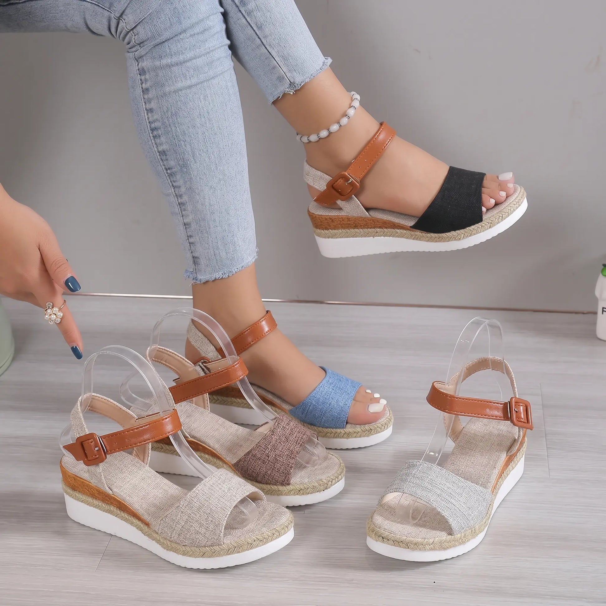 A stylish ensemble showcasing Elarae espadrille wedge sandals in various colors, with one pair worn by a model on her foot, highlighting the peep-toe, jute-wrapped wedge, and buckle ankle strap.