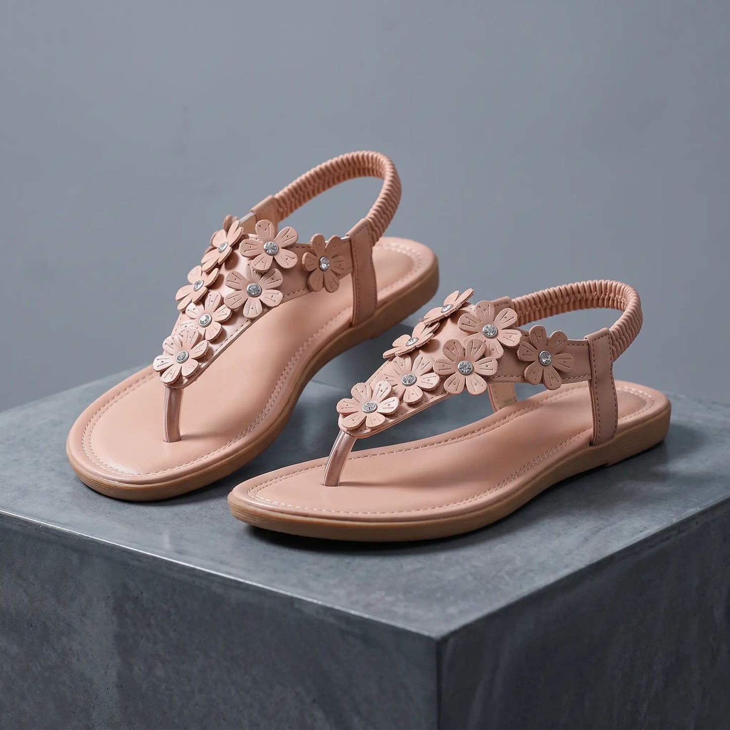 Blush apricot Elaraia bohemian flat t-strap sandals adorned with 3D sculpted flowers and clear rhinestones, featuring an elasticated slingback strap.