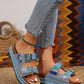 Bohemian-inspired platform slide sandals embellished with rhinestones, blue, pink, and turquoise stones, worn by a model with frayed jeans and an anklet.