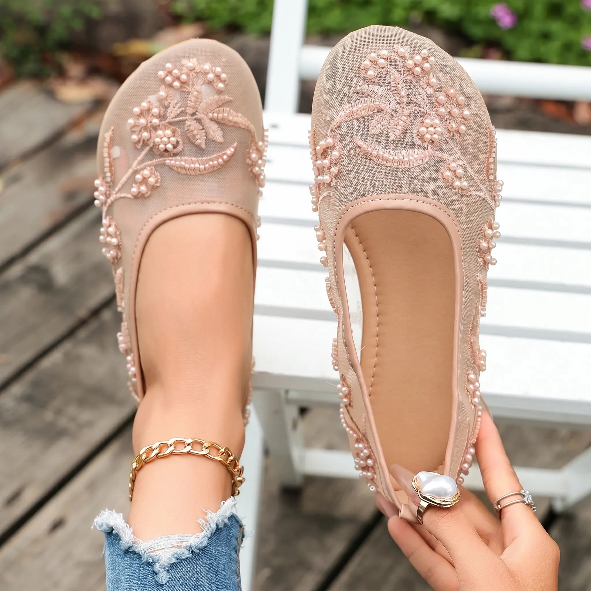 Nude sheer mesh ballet flats embellished with delicate floral embroidery, pearls, and beads, shown on feet with distressed jeans.
