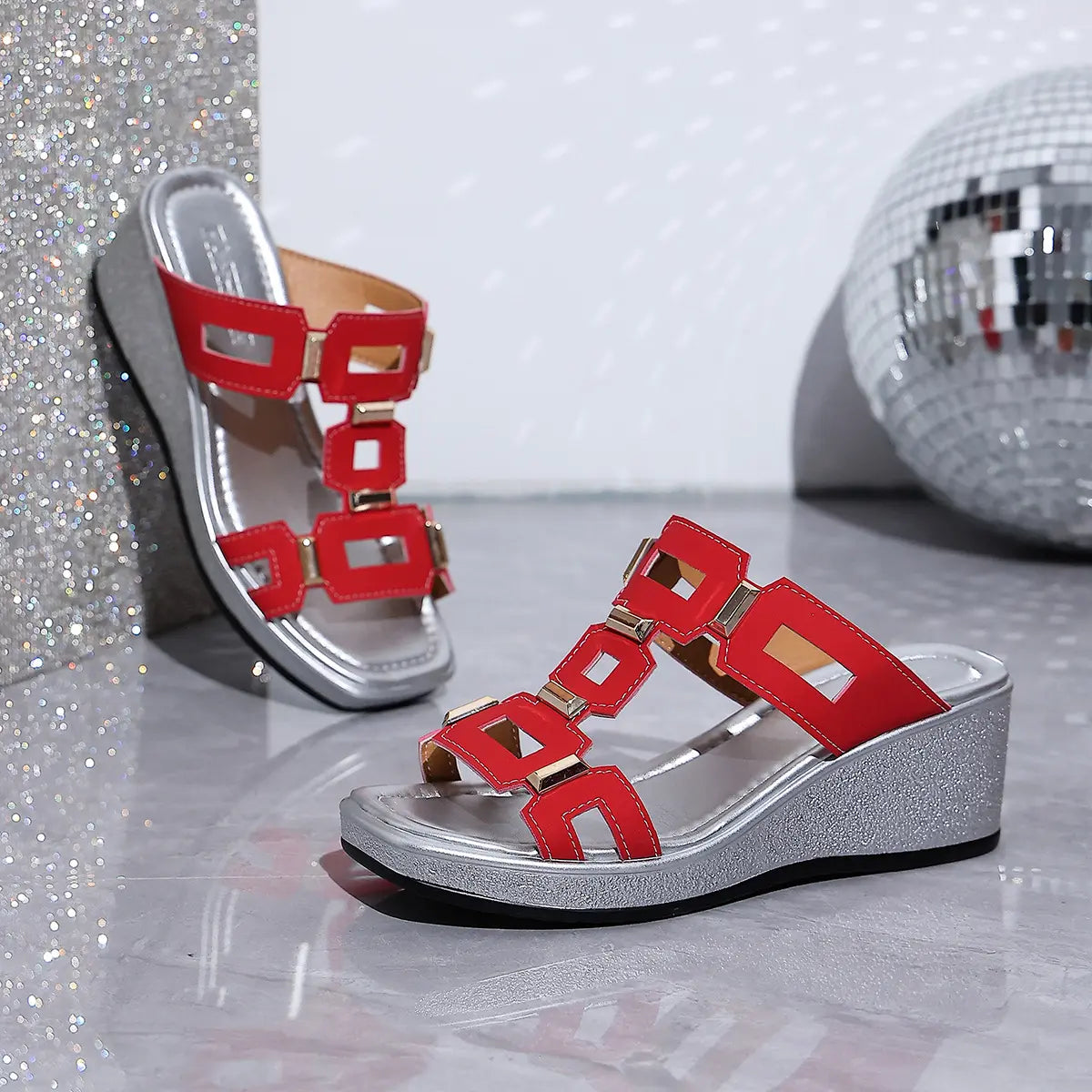 Eskari chic red platform wedge sandals with decorative geometric gold hardware and a textured metallic silver wedge heel shown from a three-quarter angle on a reflective surface with a disco ball.