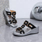 Eskari women's black slip-on wedge sandals with gold geometric hardware, featuring a textured silver wedge and open fish-mouth toe. Presented in a studio setting with a disco ball.