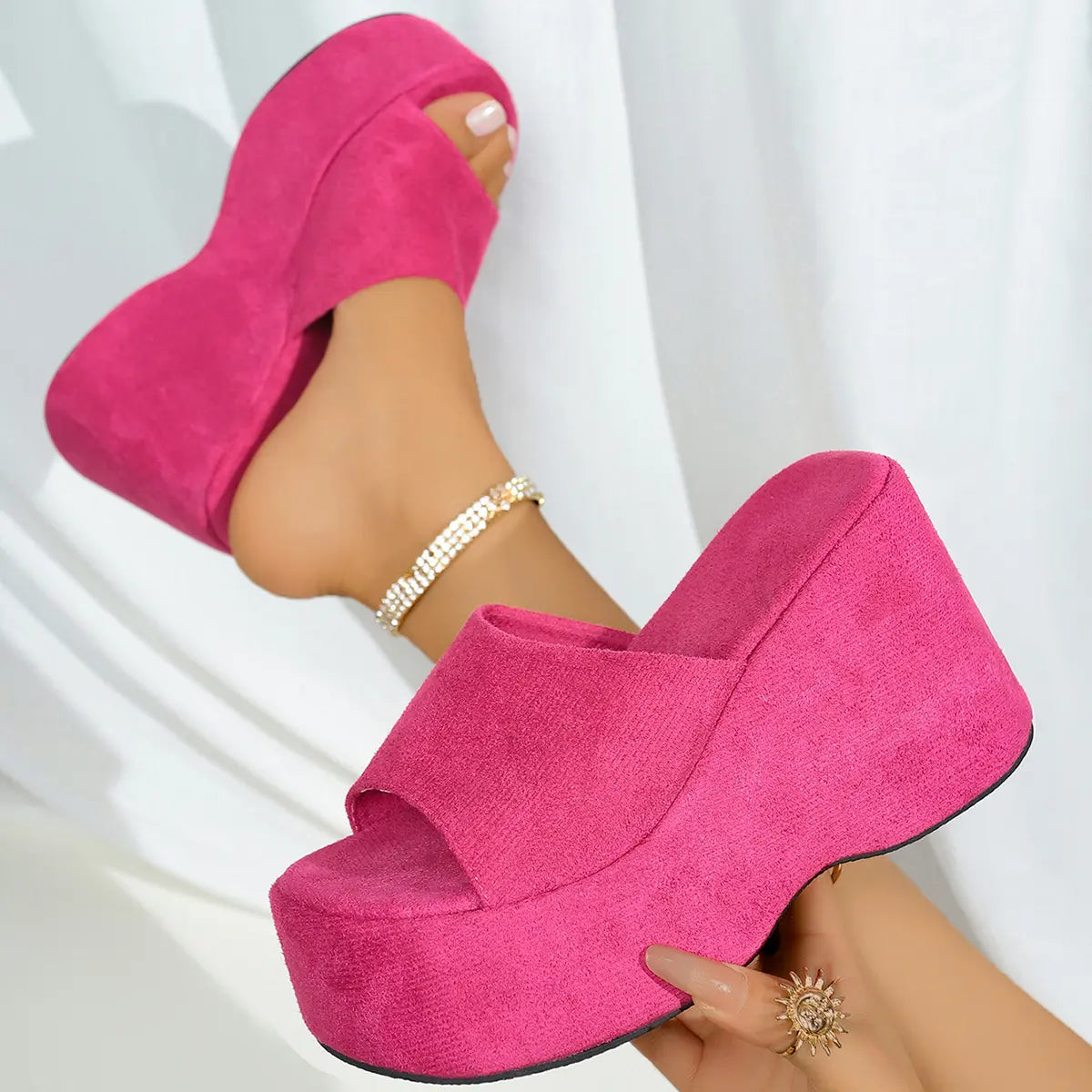 Vibrant fuchsia pink platform wedge sandals worn on a model's feet, showcasing the plush suede-like texture, single wide strap, and ultra-high continuous wedge.