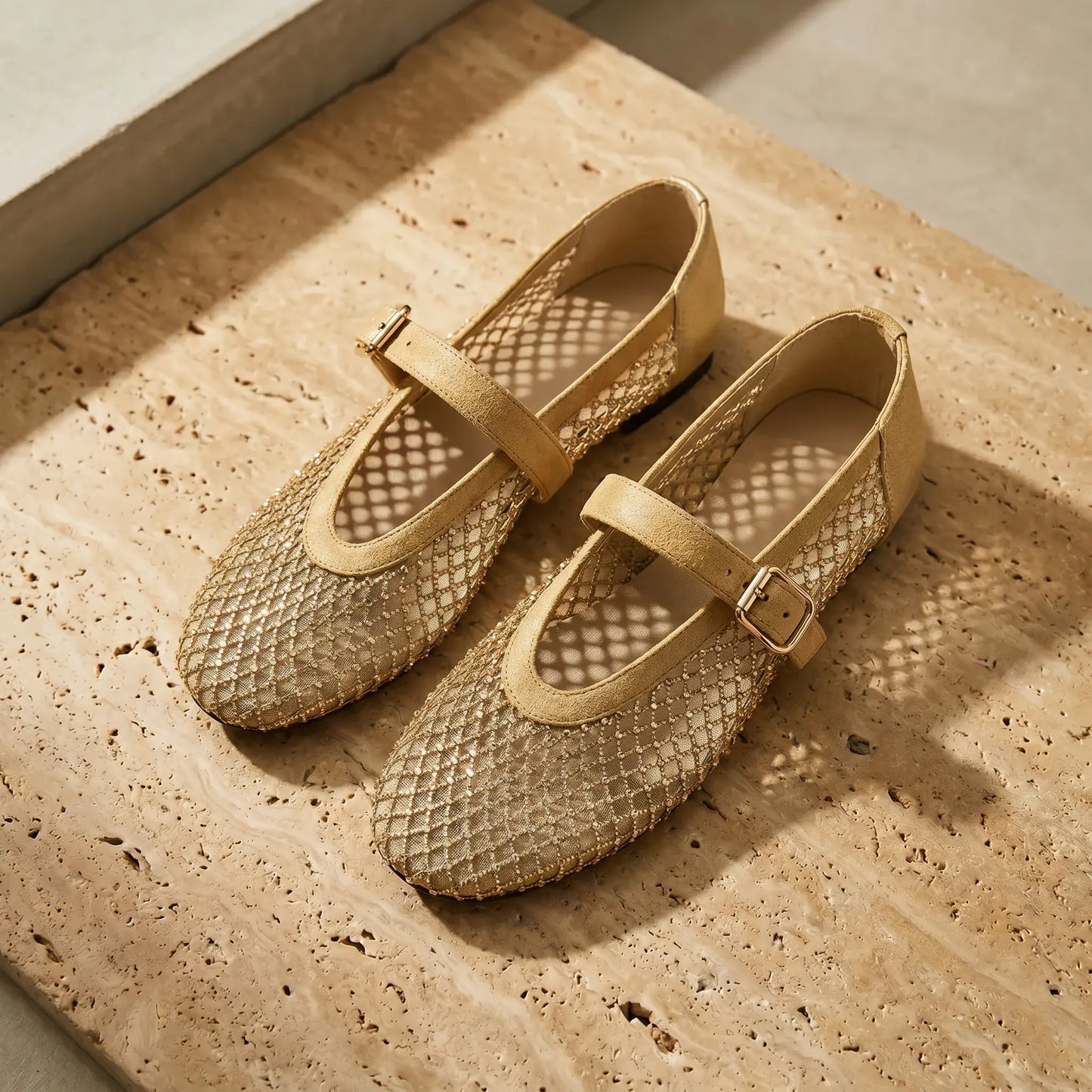 Galdyr Champagne Gold Mary Jane flats with rhinestone mesh upper and suede-finish buckle straps, displayed at an angle on a textured beige surface.