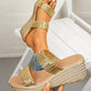 Women's gold woven strap platform wedge sandals shown on a foot and held, featuring a sculpted champagne gold wedge heel and a comfortable tan footbed.