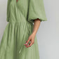 Light green cotton gauze midi wrap dress with voluminous puff sleeves, V-neckline, and a tie waist belt, displayed from the front.