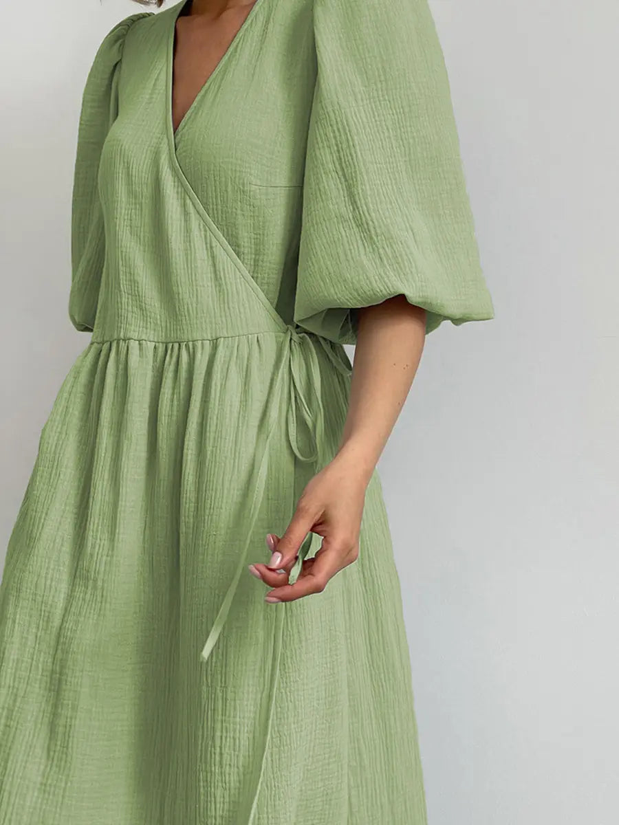 Light green cotton gauze midi wrap dress with voluminous puff sleeves, V-neckline, and a tie waist belt, displayed from the front.