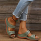 Women's green slip-on slide sandals with geometric embroidered straps, shown on a person's feet with distressed jeans and a wooden background.