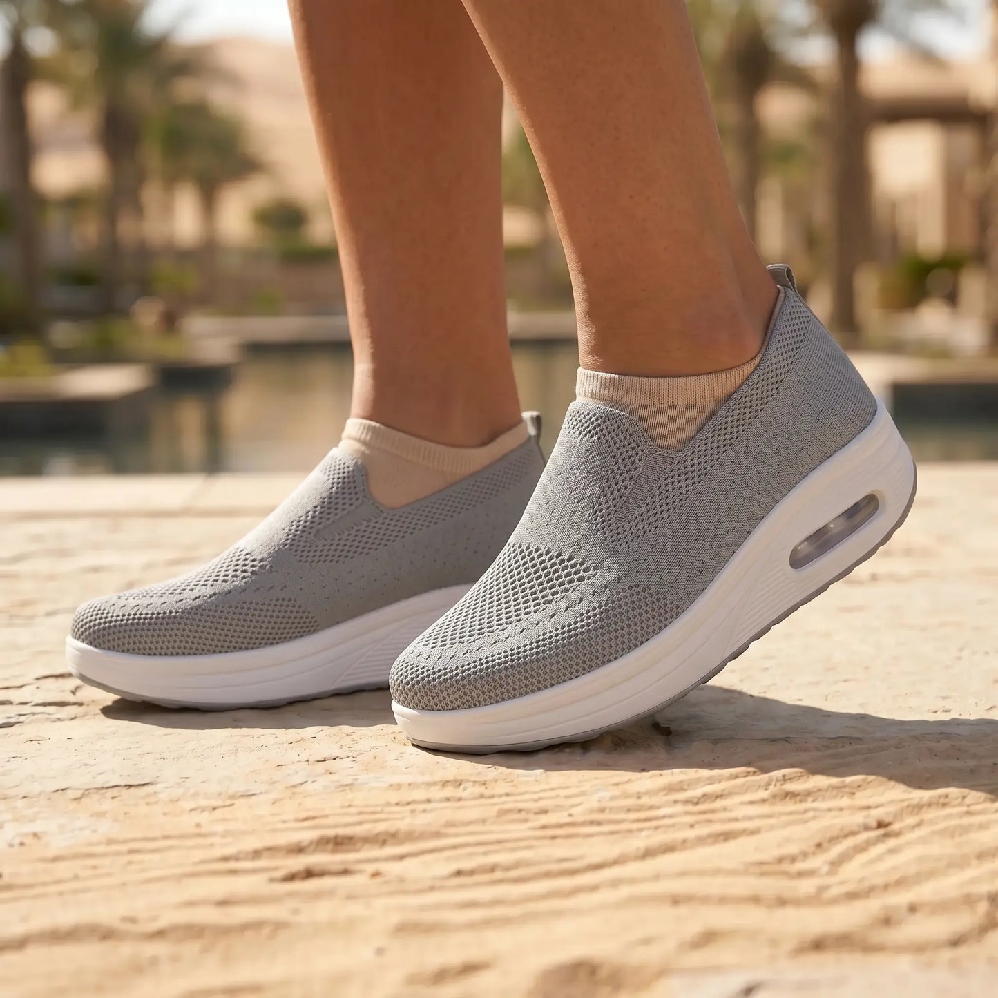 Grey Myrkos slip-on knit platform sneakers, with breathable engineered upper and white rocker sole, worn outdoors on a textured path.